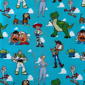 May include: A bright blue fabric featuring a repeating pattern of Toy Story characters including Buzz Lightyear, Woody, Jessie, Bo Peep, Rex, Slinky Dog, Forky, Mr. and Mrs. Potato Head, and the green aliens against a backdrop of white clouds.