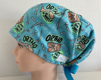 May include: A light blue surgical scrub hat with a pattern of bones, anatomical illustrations, and the text "Ortho, Do We Joints?", "Always Time For A Joint!" and "We Do Joints!"