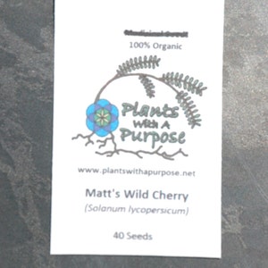 May include: A white seed packet with the text "Medicinal Seeds" and "100% Organic." The packet features a logo with a blue and green floral design and the words "Plants With A Purpose." It lists "Matt's Wild Cherry" and 40 seeds.