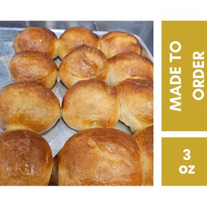 May include: A tray of freshly baked, golden-brown rolls. The rolls are round and have a glossy finish. The image includes text that reads "MADE TO ORDER" and "3 oz."