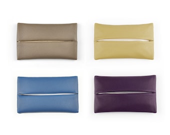 Può includere: Quattro copri scatola di fazzoletti di diversi colori: marrone, giallo, blu e viola. Ogni copertura ha una forma rettangolare con una fessura per i fazzoletti.