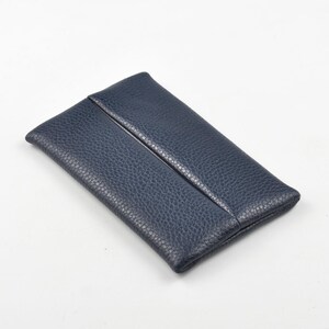 Pu&ograve; includere: Una pochette rettangolare blu navy realizzata in pelle testurizzata e granulata. L'accessorio presenta un design pulito con una singola cucitura verticale che corre lungo il centro del pannello frontale, creando un oggetto semplice e funzionale.