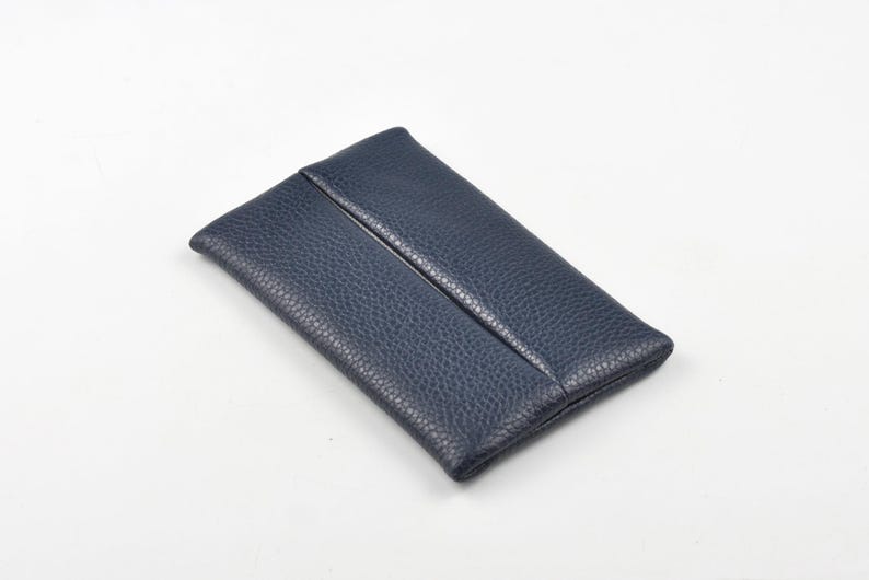 Pu&ograve; includere: Una pochette rettangolare blu navy realizzata in pelle testurizzata e granulata. L'accessorio presenta un design pulito con una singola cucitura verticale che corre lungo il centro del pannello frontale, creando un oggetto semplice e funzionale.