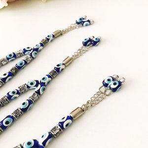May include: Three blue and white evil eye bead necklaces with silver accents and chain attachments.