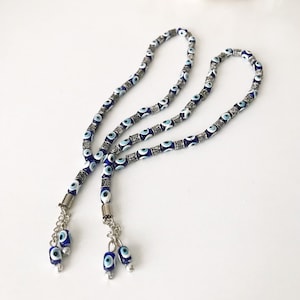 May include: Two blue and white evil eye bead prayer beads with silver accents and tassels. The beads are strung on a silver chain.