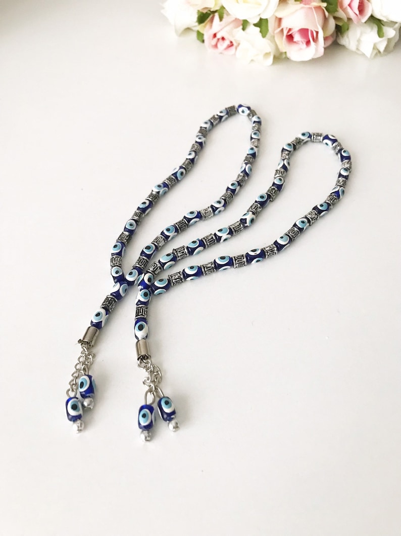 May include: Two blue and white evil eye bead prayer beads with silver accents and tassels. The beads are strung on a silver chain.