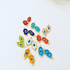 May include: Assortment of colorful evil eye charms with gold accents. The charms are oval shaped and have a blue eye in the center. They are perfect for jewelry making or crafting.