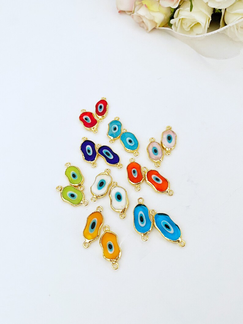 May include: Assortment of colorful evil eye charms with gold accents. The charms are oval shaped and have a blue eye in the center. They are perfect for jewelry making or crafting.