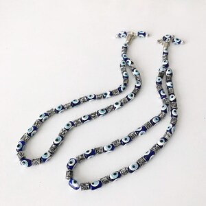 May include: A double strand necklace with blue and white evil eye beads and silver accents.
