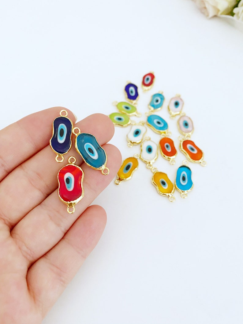 May include: Assortment of colorful evil eye charms with gold-toned metal accents. The charms are shaped like an oval with a blue eye in the center. The charms are perfect for adding a touch of protection and good luck to jewelry, keychains, and other crafts.