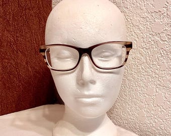 May include: Brown and white tortoiseshell eyeglasses with clear lenses on a white mannequin head.