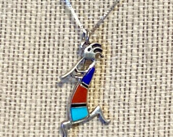 May include: A silver necklace with a turquoise, red, and blue inlay pendant depicting a stylized Native American dancer.