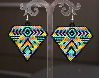 May include: Diamond-shaped beaded earrings with a geometric pattern. The earrings feature a black outline with a colorful interior design of turquoise, orange, yellow, and purple beads. The earrings hang from silver-colored hooks.