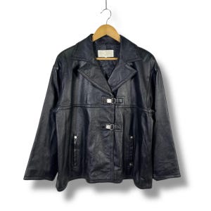May include: A black leather jacket with a silver buckle closure and a collar. The jacket has a slightly oversized fit and a relaxed silhouette.