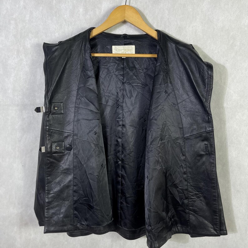 May include: A black leather jacket with a button closure and a zippered pocket. The jacket has a lined interior and a collar.