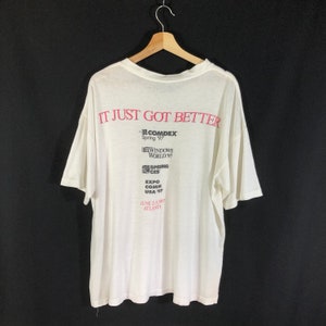 May include: White t-shirt with the text "IT JUST GOT BETTER" in pink lettering. The back of the shirt features logos for Comdex Spring '97, Windows World '97, Spring CES, Expo Comm USA '97, and the dates June 2-5, 1997 and Atlanta.
