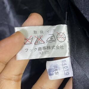 May include: A white tag with Japanese text and symbols for washing instructions. The tag reads "フク商事株式会社" (Fukushoji Kabushiki Kaisha) and "K1-175". A smaller white tag with Japanese text reads "日本製" (Made in Japan) and "54010".