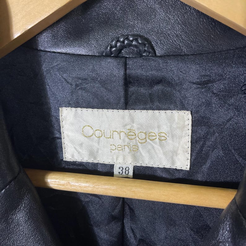 May include: Black leather jacket with a label that reads "Courr&egrave;ges Paris" and a size tag that says "38".