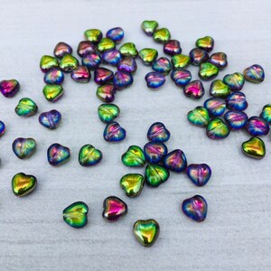 May include: A scattering of iridescent heart-shaped glass beads in shades of green, blue, and purple.