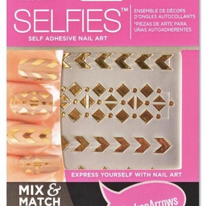 以下が含まれることがあります： Cina Nail CreationsのSelfiesというラベルが付いた、金色の自己粘着性ネイルアートステッカーシート。パッケージはピンクと黒のデザインで、#BrokenArrowsというテキストがあり、矢印やひし形を含む様々な幾何学模様が表示されています。