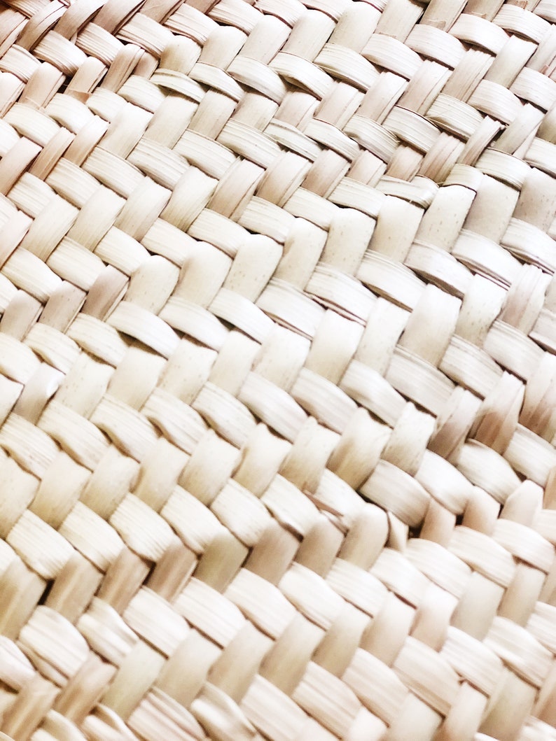 Op de afbeelding: Close-up van een geweven rieten textuur. De weving is gemaakt van natuurlijk, lichtbruin materiaal, waardoor een patroon van vierkanten ontstaat.
