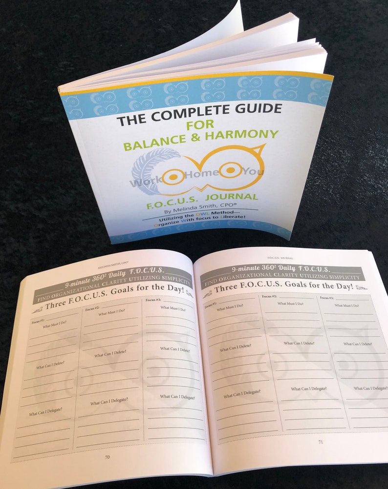 May include: An open book with a blue and yellow owl design on the cover. The title of the book is "The Complete Guide for Balance & Harmony Work Home You F.O.C.U.S. Journal". The book has a section titled "9-minute 360&deg; Daily F.O.C.U.S. Find Organizational Clarity Utilizing Simplicity Three F.O.C.U.S. Goals for the Day!" with a table for listing goals.