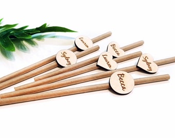 May include: A set of six brown paper straws with personalized wooden toppers. The toppers are round and heart-shaped and feature the names "Sydney", "Lauren", and "Becca".