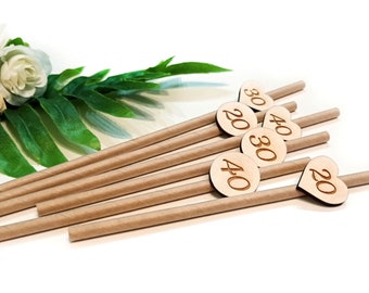 May include: Set of brown paper straws with wooden heart-shaped and round tags. The tags are engraved with the numbers 20, 30, and 40.