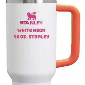 Puede incluir: Un vaso Stanley blanco de 40 oz con tapa verde ne&oacute;n, pajita rosa y asa naranja. El frente presenta un logotipo de oso rosa sobre el texto "STANLEY", "WHITE NEON" y "40 OZ. STANLEY" impreso en letras de color rosa y naranja.
