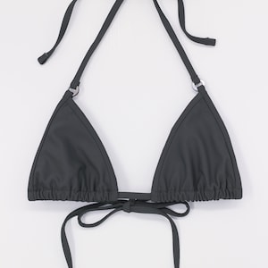 May include: A dark grey triangle bikini top with adjustable straps and ties. The top has a simple design and is made of a smooth, stretchy fabric.