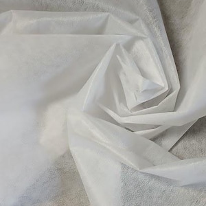 Könnte beinhalten: Nahaufnahme eines weißen, durchscheinenden Stoffes mit weicher, strukturierter Optik. Der Stoff ist gefaltet und gewirbelt, wodurch ein spiralförmiges Muster in der Mitte entsteht. Das Material scheint leicht und zart zu sein.