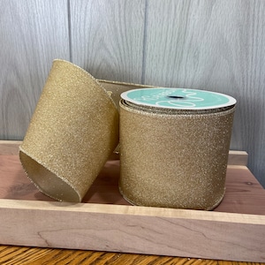 May include: Two spools of gold glitter ribbon with a white label on one spool that says "Boutique Ribbon".