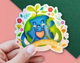 Pode incluir: Um adesivo holográfico com uma Terra de desenho animado segurando um coração com o texto "Mother Earth Day April 22". A Terra é azul e verde com um rosto sorridente e flores ao redor.