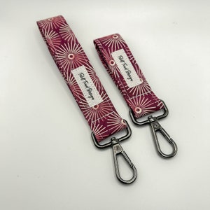 May include: Two red and white patterned keychains with silver swivel clips. The keychains have the text "Felt Food Design" printed on them.