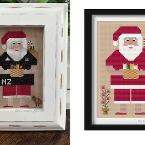 May include: Cross-stitch artwork of Santa Claus in a red suit and hat, holding gifts. The image features a tan background, a black frame, and the text "the french giraffe" at the bottom. A kiwi bird and flowers are also included.