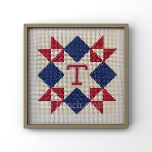 May include: A framed cross-stitch design featuring a red, white, and blue quilt block pattern with the letter "T" in the center.