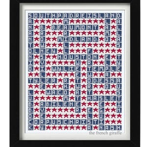 May include: Framed art print featuring a grid of Texas city names spelled out in letter tiles, each row interspersed with red star graphics. The print is in a black frame and includes the text "the french giraffe".