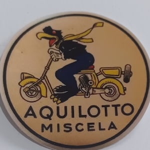 Op de afbeelding: Een geel en zwart cartoonfiguur rijdt op een gele scooter met de tekst "Aquilotto Miscela" op een beige achtergrond.