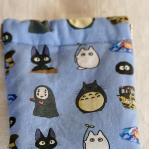 May include: A blue drawstring bag with a variety of cartoon characters from the Studio Ghibli films, including Totoro, No Face, and Jiji the cat.