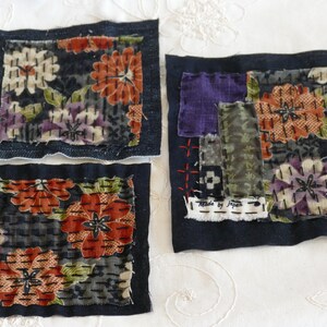 May include: Four fabric squares with floral patterns, each with a black border. The squares are made of different fabrics and have different stitching patterns. One square has a label that says "Made by Japan".