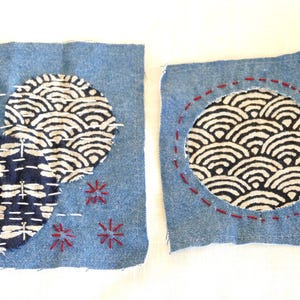 May include: Two denim squares with fabric appliques. The first square has two circles of fabric with a wave pattern and a dragonfly pattern. The second square has a circle of fabric with a wave pattern. Both squares have red embroidery.