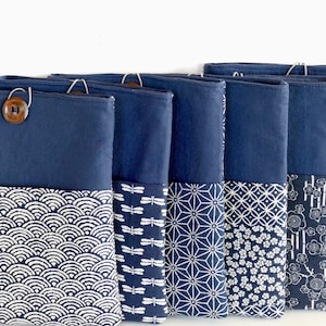May include: Five blue fabric pouches with different Japanese-inspired patterns. The pouches have a flap with a button closure. The patterns include waves, dragonflies, geometric shapes, flowers, and a traditional Japanese design.
