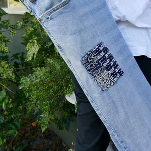 May include: A light blue denim yoga mat bag with a black and white patterned fabric patch sewn on the front.