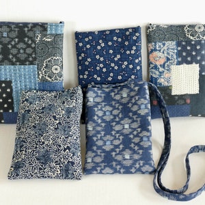 May include: Five small blue fabric pouches with different patterns. The pouches are made of a patchwork of blue and white fabrics. One pouch has a long strap.