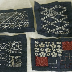 May include: Four small squares of indigo fabric with white stitching, each with a different pattern. The squares are numbered 1 through 4.
