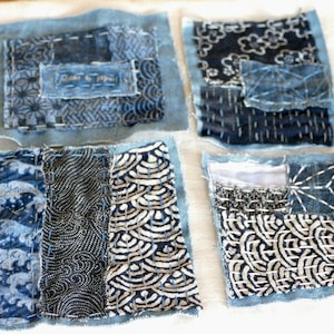 May include: Four square fabric patches with denim borders. Each patch features a unique combination of indigo-dyed fabrics with various patterns, including floral, geometric, and wave designs. Visible stitching and the text "Made by Japan" add to the handcrafted aesthetic.