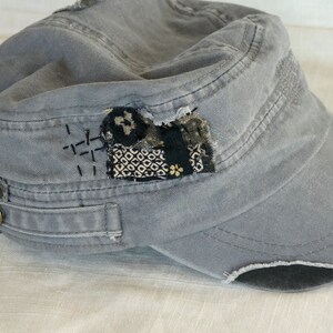Peut inclure: Une casquette en toile grise &agrave; l'aspect us&eacute;. La casquette a un patch cousu sur le devant avec un motif g&eacute;om&eacute;trique noir et blanc. La casquette a un petit bouton m&eacute;tallique sur le c&ocirc;t&eacute;.
