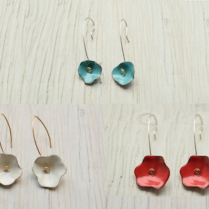 Peut inclure: Un ensemble de trois paires de boucles d'oreilles pendantes avec un motif floral. Les boucles d'oreilles sont en métal et ont un fil de couleur or. Les fleurs sont disponibles en turquoise, blanc et rouge.