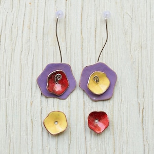 Peut inclure: Une paire de boucles d'oreilles pendantes avec un motif de fleur violet, jaune et rouge. Les boucles d'oreilles sont en métal et ont une fermeture simple à crochet.