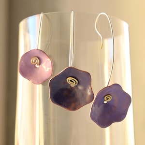 Peut inclure: Trois paires de boucles d'oreilles avec des pendentifs en forme de fleur de couleur violette et lavande et des accents dorés.